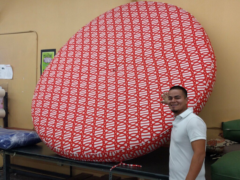 A man standing next to an umbrella that is covered in red and white letters.