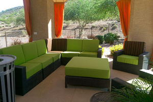 A patio with green furniture and orange curtains.