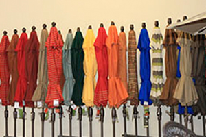 A row of umbrellas hanging on poles in front of a wall.